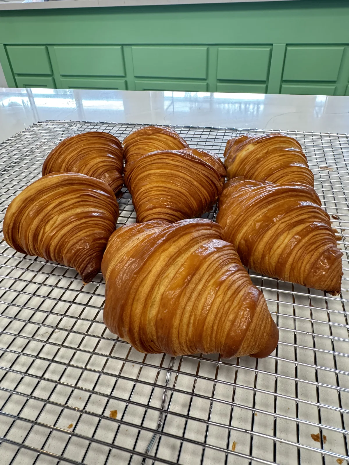 Fresh croissants cooling on the rack at The Cake Pantry, Fishers — laminated from scratch daily